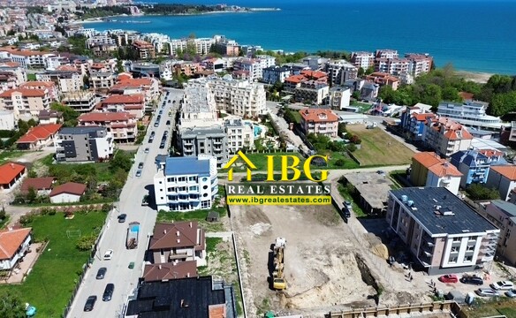 Aerial view of a seaside town with a construction site in the foreground and the blue sea in the background.